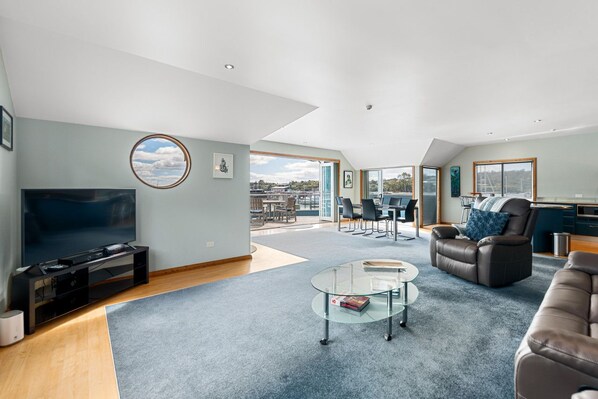 A spacious living area with a flat-screen TV, a glass coffee table, and a comfortable sofa.