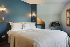 A bedroom with a large bed, a wooden headboard, and a small table with luggage.