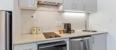 A compact kitchen with a dishwasher, a coffee maker, and a sink.