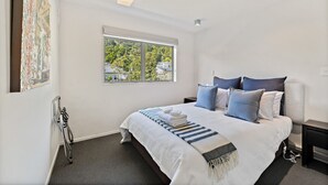 Un dormitorio moderno con una cama grande, una ventana con vista a la ciudad y un cuadro en la pared.