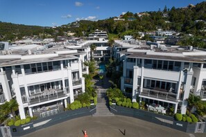 A modern hotel with a central courtyard, multiple floors, and a view of the surrounding hillside. - Paihia 2 Bdrm Apartment and Pool (Paihia)