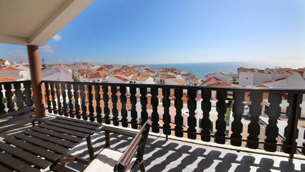 Un balcón con vistas a un pueblo costero y al mar.