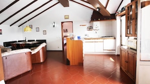 Una cocina amplia con comedor, vigas de madera en el techo y piso de baldosas.