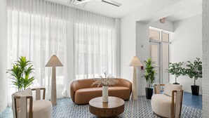 A modern living room with a sofa, two armchairs, a coffee table, and potted plants. - Global Luxury Suites at The Apex Miami (Miami Beach)