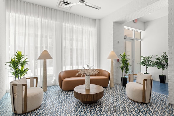 A modern living room with a sofa, two armchairs, a coffee table, and potted plants. - Global Luxury Suites at The Apex Miami (Miami Beach)