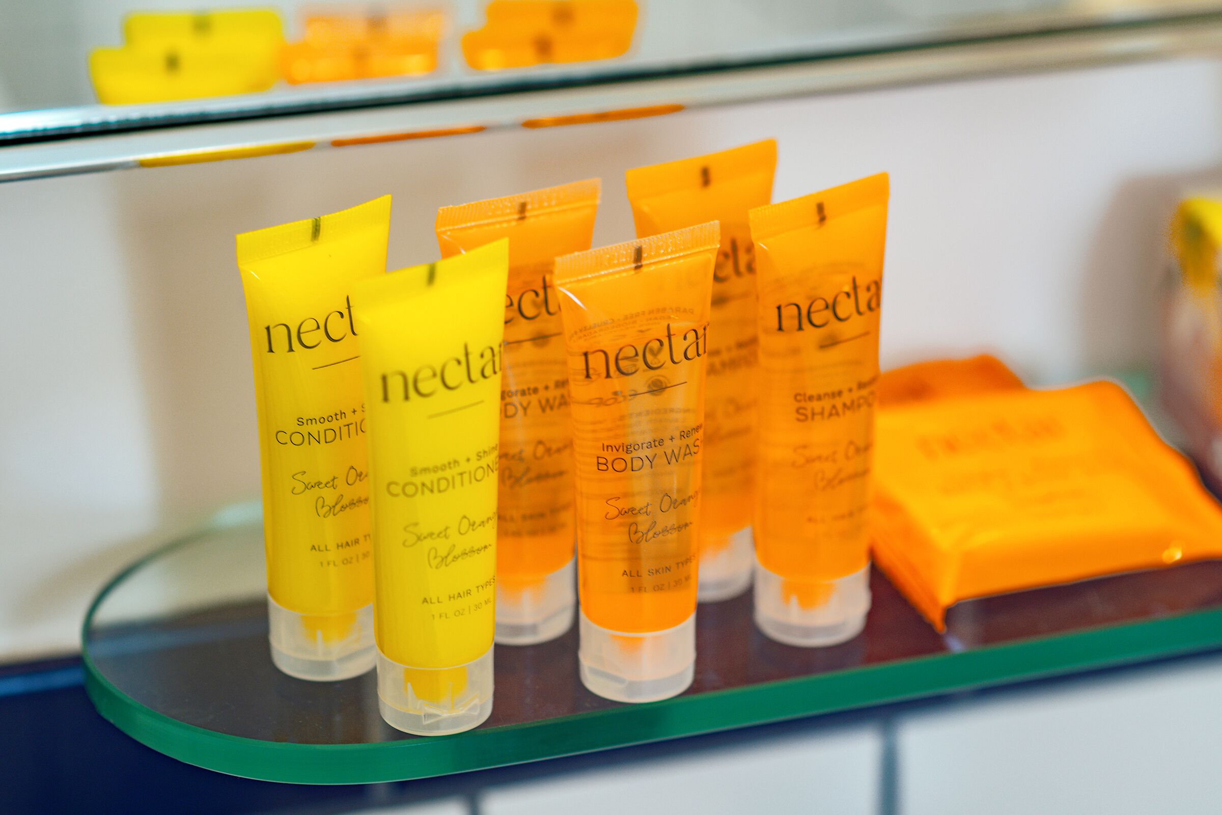A display of Neectar body wash and conditioner bottles on a glass shelf.