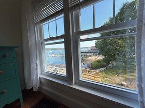 A room with a window overlooking a dock and water. - Heron's Landing (Harpswell)