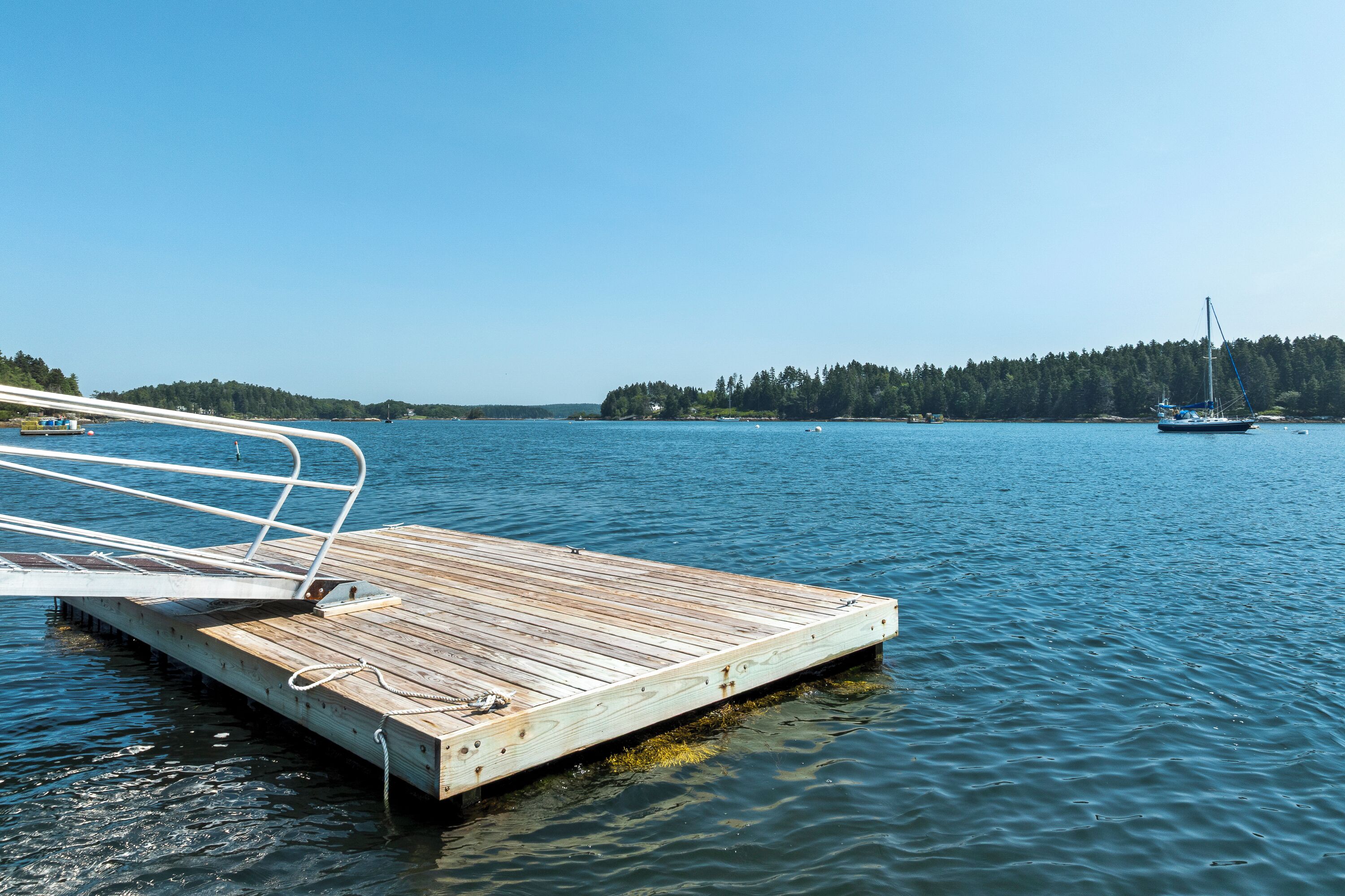 A wooden dock extending into calm water with a clear sky above.