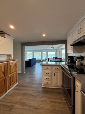Une cuisine moderne avec des meubles en bois, un îlot central et une vue sur l’extérieur.