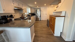 A modern kitchen with white cabinetry, stainless steel appliances, and a wooden island. - Heron's Landing (Harpswell)