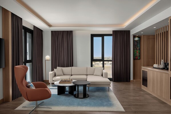 A modern living room with a sofa, a chair, a coffee table, and a flat-screen TV. - Courtyard By Marriott Dakar Diamniadio (Diamniadio)