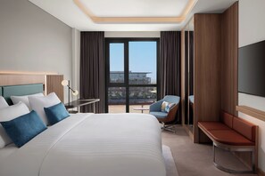 A modern hotel room with a large bed, a desk, a chair, and a TV. - Courtyard By Marriott Dakar Diamniadio (Diamniadio)