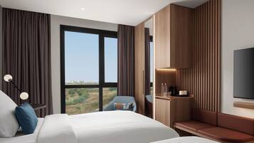 Una habitación de hotel moderna con una cama grande, una zona de estar, un escritorio con lámpara y un televisor.