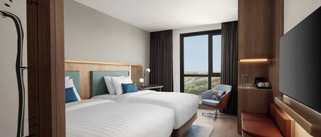 A hotel room with two beds, a TV, a desk, a chair, and a view of the outdoors.