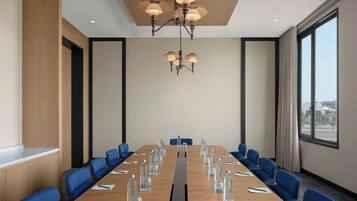A conference room with a long table, blue chairs, and a chandelier.