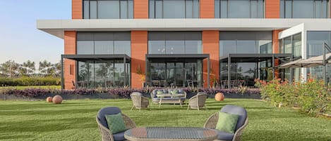 Un edificio moderno con techo plano, ventanas amplias y un césped cuidado con mobiliario exterior.
