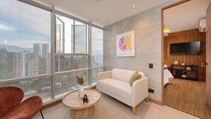 Un salon moderne avec une grande fenêtre, un canapé blanc, un fauteuil rouge et une table basse ronde.