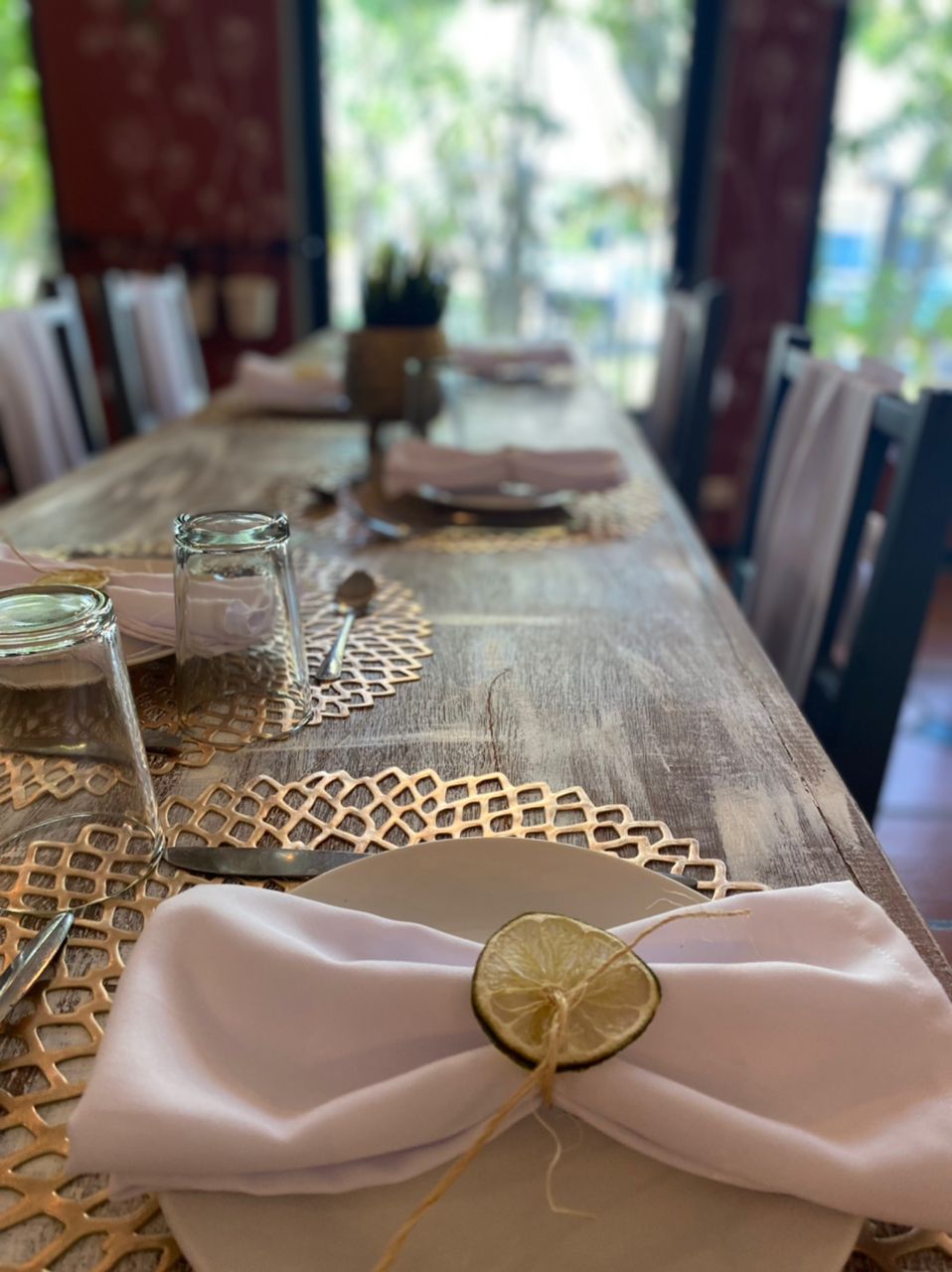A dining table set with a lace placemat, a glass jar, and a napkin tied with a string.