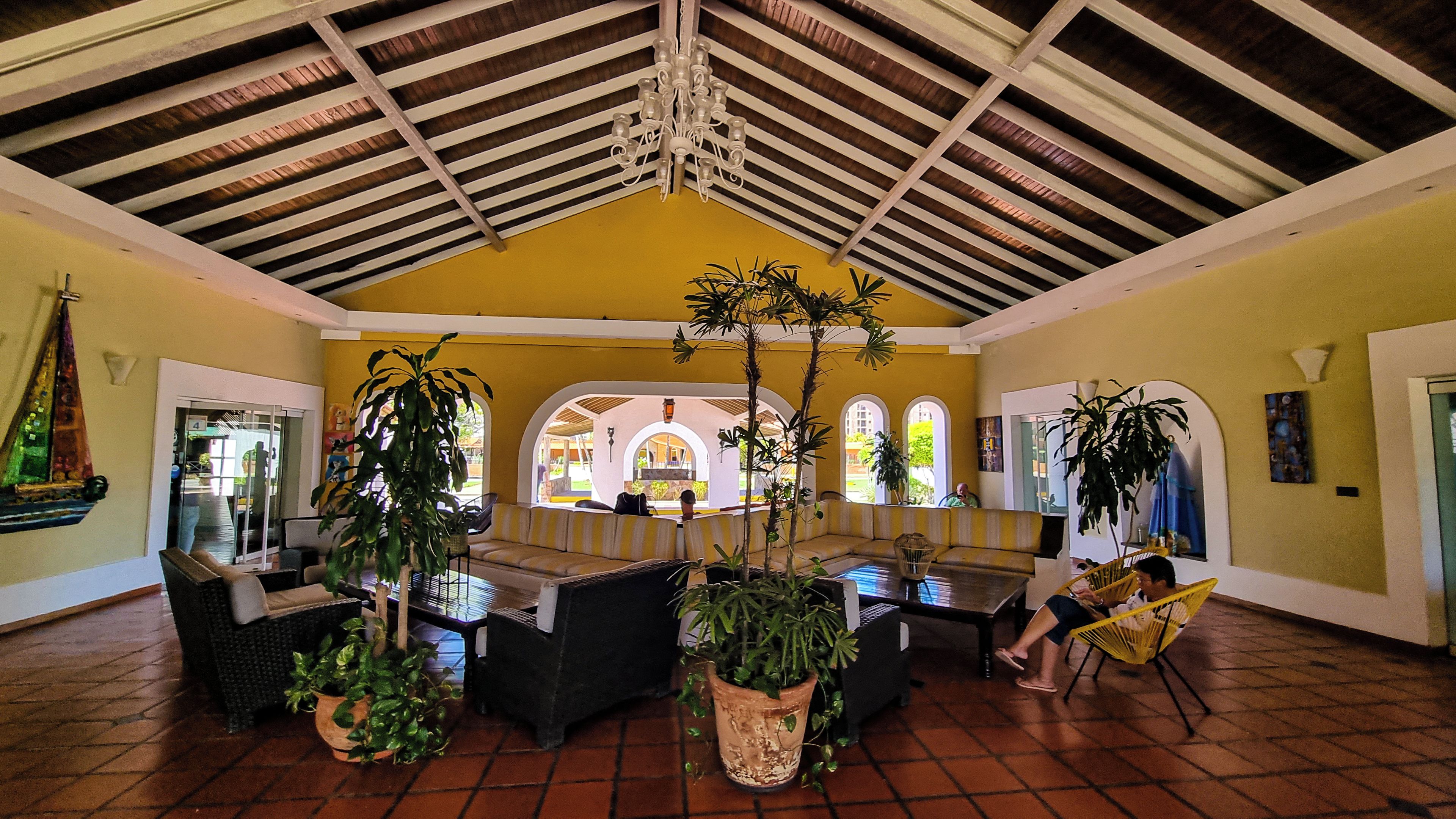 A spacious indoor area with a high ceiling, multiple seating arrangements, and potted plants.