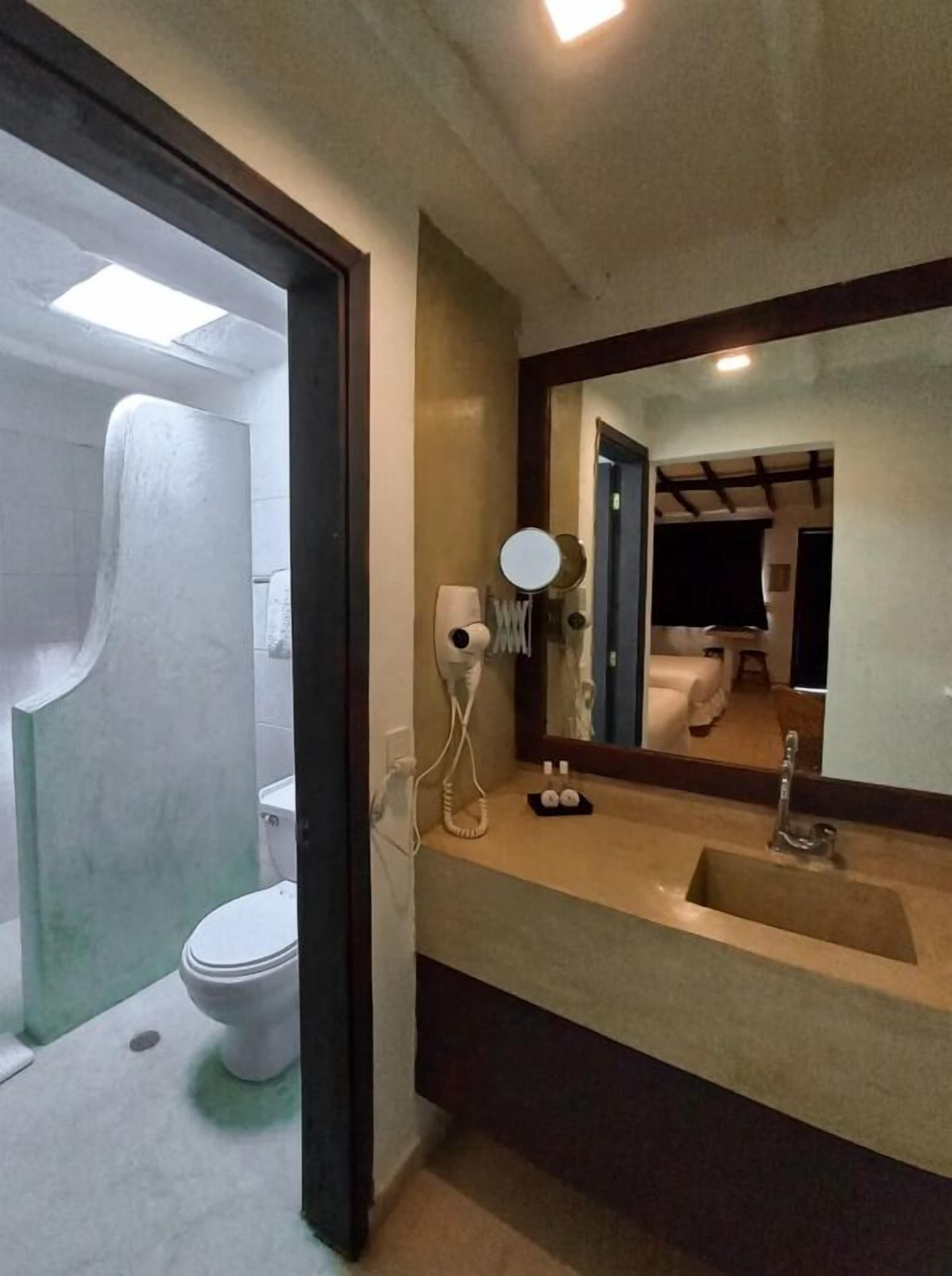 Un bagno con il water, un lavandino e uno specchio.