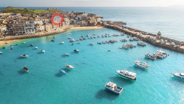 Une ville côtière dotée d’un port rempli de bateaux, d’une plage de sable et de bâtiments qui bordent la côte.