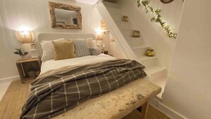 Un dormitorio con una cama, lámparas de noche, un espejo y un banco.