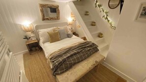 A bedroom with a bed, bedside tables, a mirror, and a bench. - Award Winning "Smuggler's Cabin" A Basement Studio (St Ives)