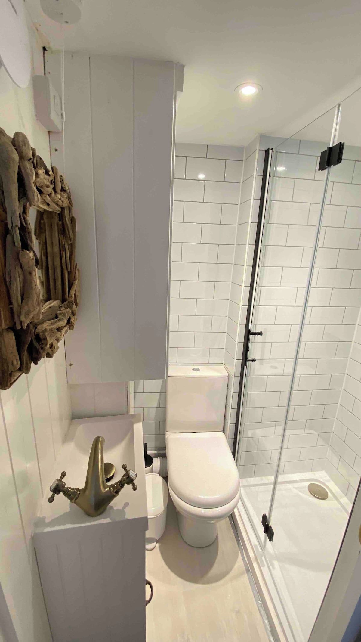 A bathroom with a white toilet, a glass-enclosed shower, and a decorative wooden piece on the wall.