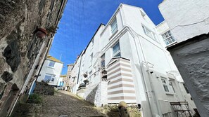 A narrow cobblestone street flanked by white buildings with multiple windows and balconies. - Award Winning "Smuggler's Cabin" A Basement Studio (St Ives)