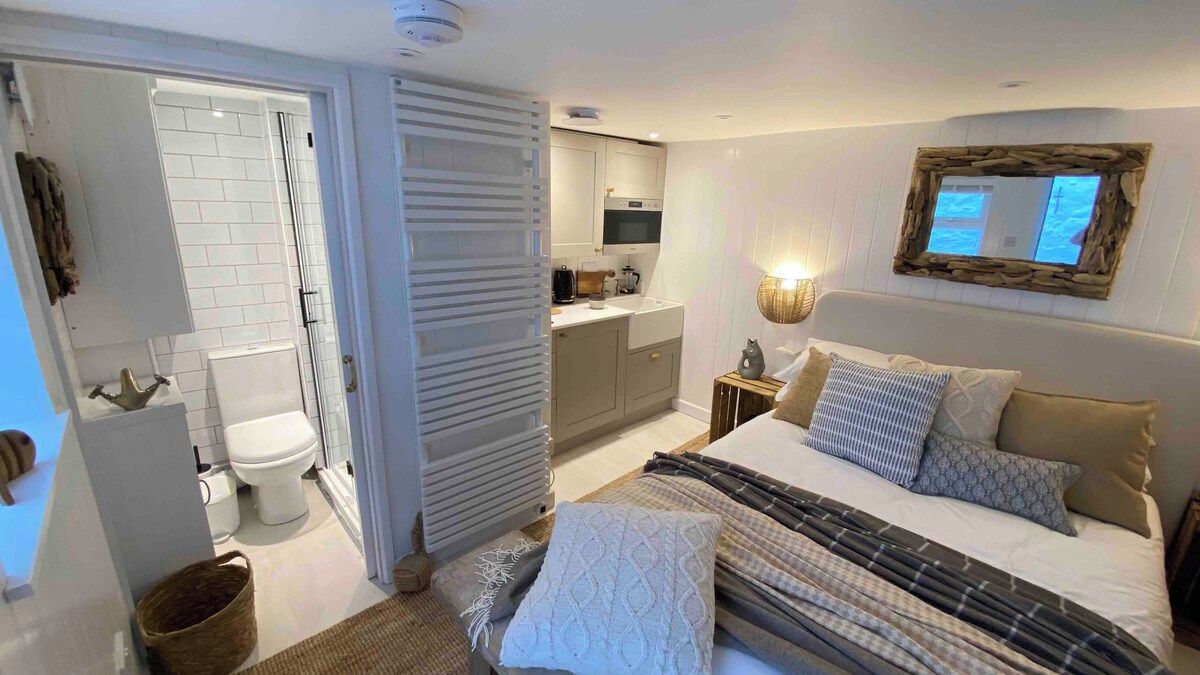 Un dormitorio con cama, mesita de noche y un espejo en la pared.