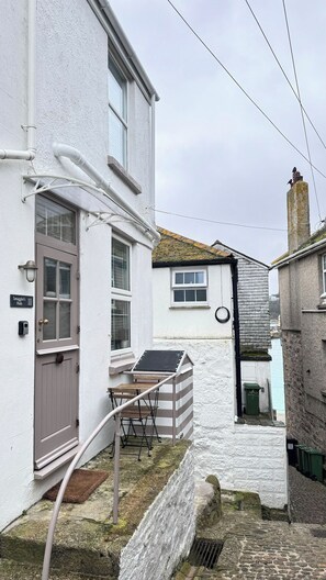 A narrow street with a white building, a door labeled 'Smuggler's Hide 11', and a small window. - Award Winning "Smuggler's Cabin" A Basement Studio (St Ives)