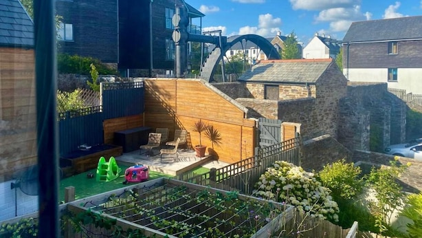 A courtyard with a wooden deck, seating area, and a stone wall. - Stunning Coastal Retreat -mins From Harbour/beach (St Austell)