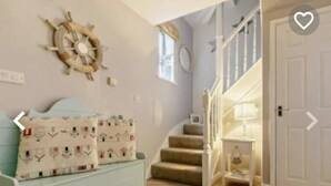 A cozy room with a light blue sofa, a decorative wall with a ship's wheel, and a staircase leading to another level. - Stunning Coastal Retreat -mins From Harbour/beach (St Austell)