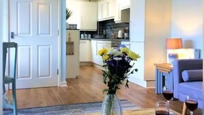 A living room with a wooden coffee table, two wine glasses, and a vase with flowers. - Stunning Coastal Retreat -mins From Harbour/beach (St Austell)