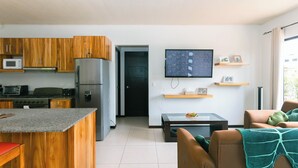 Una cocina moderna con armarios de madera, un refrigerador, microondas y un comedor con mesa y sillas.