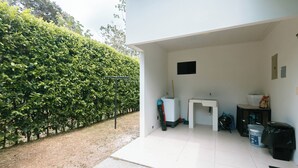 Una habitación limpia con paredes blancas, un escritorio pequeño, un cubo de basura y un dispensador de agua.