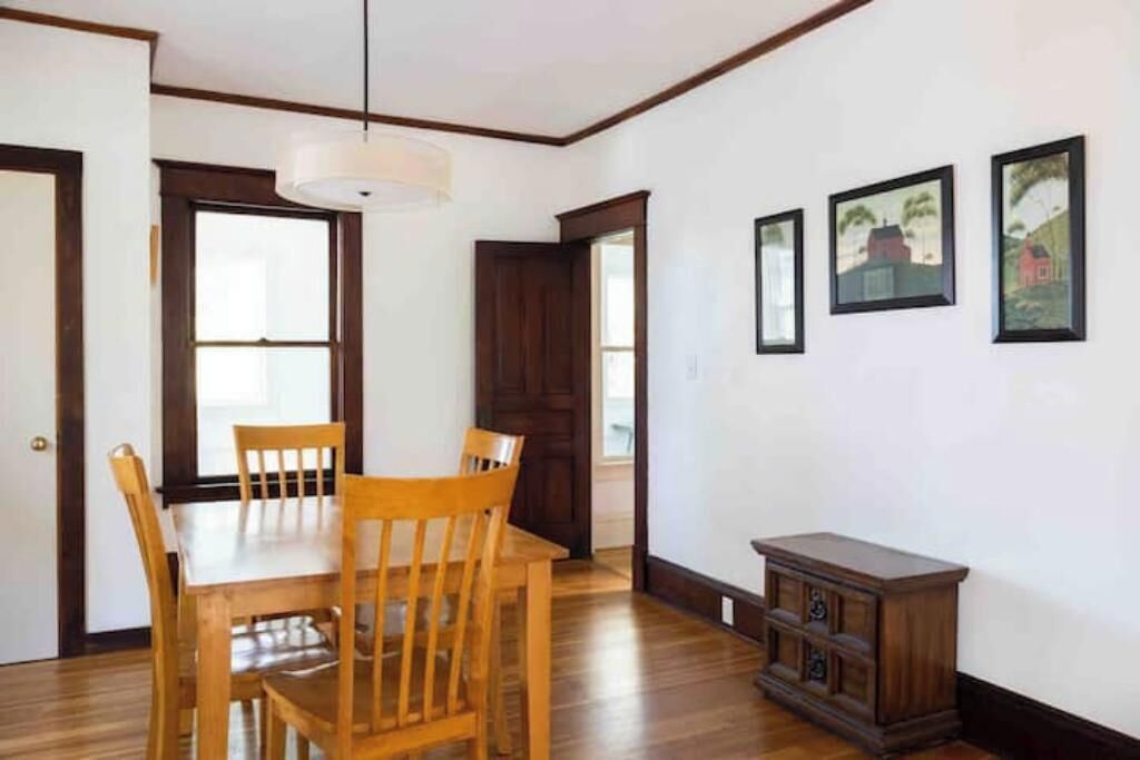 Un comedor con una mesa y sillas de madera, una lámpara colgante y un mueble pequeño.
