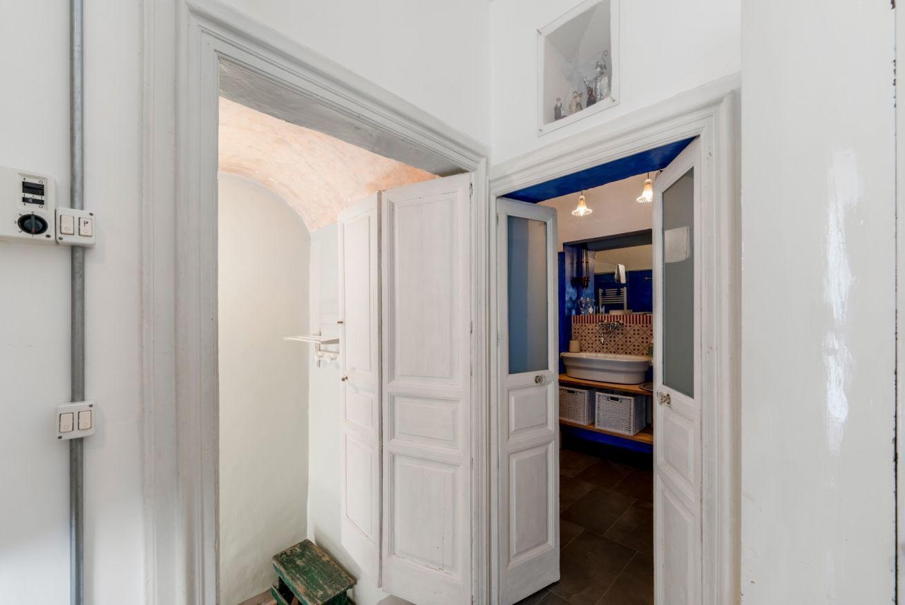 A hallway with white doors, a utility box, and a blue wall with shelves.