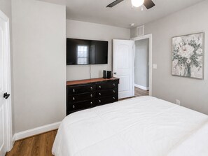 A bedroom with a bed, a dresser, a television, and a door leading to another room. - Private Villa 3-Bed|  7 min from Downtown (Raleigh)