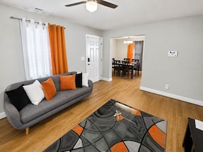 A living room with a grey sofa, a coffee table, and a dining area with a table and chairs.