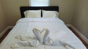 Una cama bien hecha con sábanas blancas y dos toallas dispuestas en forma de cisne.