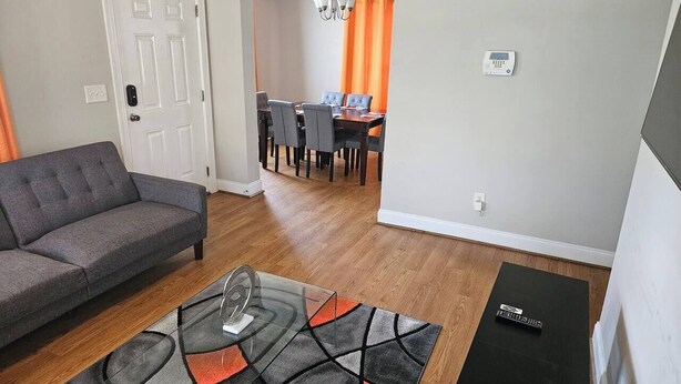 Una sala de estar con sofá, una mesa de centro de vidrio y un comedor con mesa y sillas.