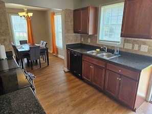 A modern kitchen with dark wooden cabinets, a granite countertop, and a dishwasher.