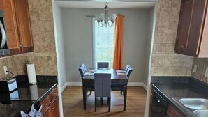 Una cocina moderna con armarios de madera, una isla central y un comedor con una araña.