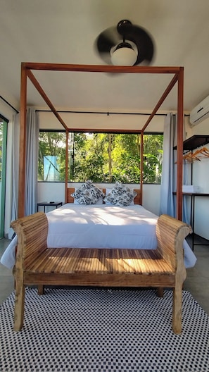 A bedroom with a four-poster bed, a ceiling fan, and a view of greenery through large windows. - Luxurious 4-bedroom villa with AC, WiFi in superb Paraty - RJ (Paraty)