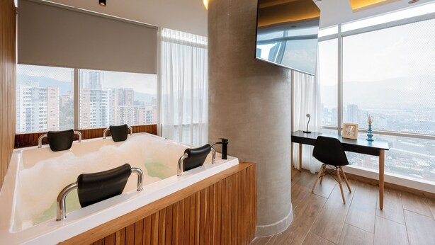 A modern bathroom with a large bathtub, a wooden vanity, and a desk with a chair. - Impressive 2BR apt with Jacuzzi & A/C in El Poblado (Medellín)