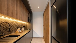 A modern kitchen with a stainless steel refrigerator, wooden cabinets, and a herringbone-patterned backsplash. - Impressive 2BR apt with Jacuzzi & A/C in El Poblado (Medellín)