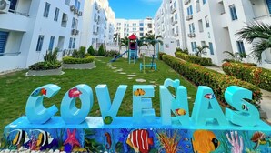 A modern apartment complex with a central courtyard, a children's play area, and a sign reading "COVENAS". - Family apartment, Coveñas, Caribe Campestre (Coveñas)