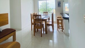 A dining area with a table and chairs, a ceiling fan, and a TV mounted on the wall. - Family apartment, Coveñas, Caribe Campestre (Coveñas)