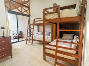 Una habitación con literas, un aparador y una puerta corrediza de vidrio que da a un espacio al aire libre.